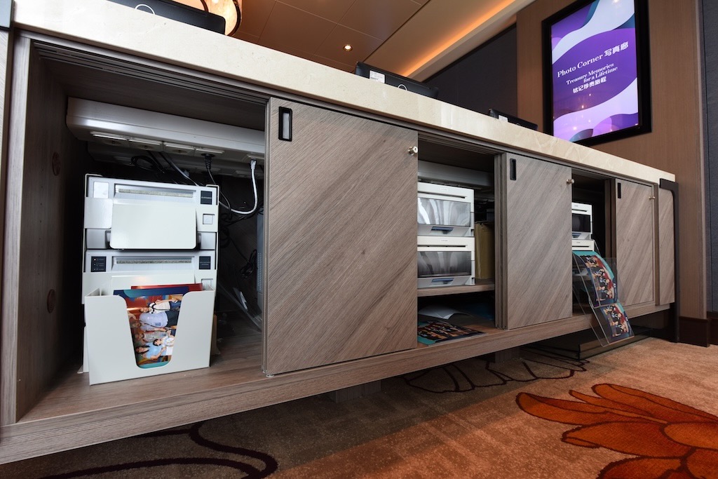 Image of printers printing out photographs behind a counter where guests purchase their photos.