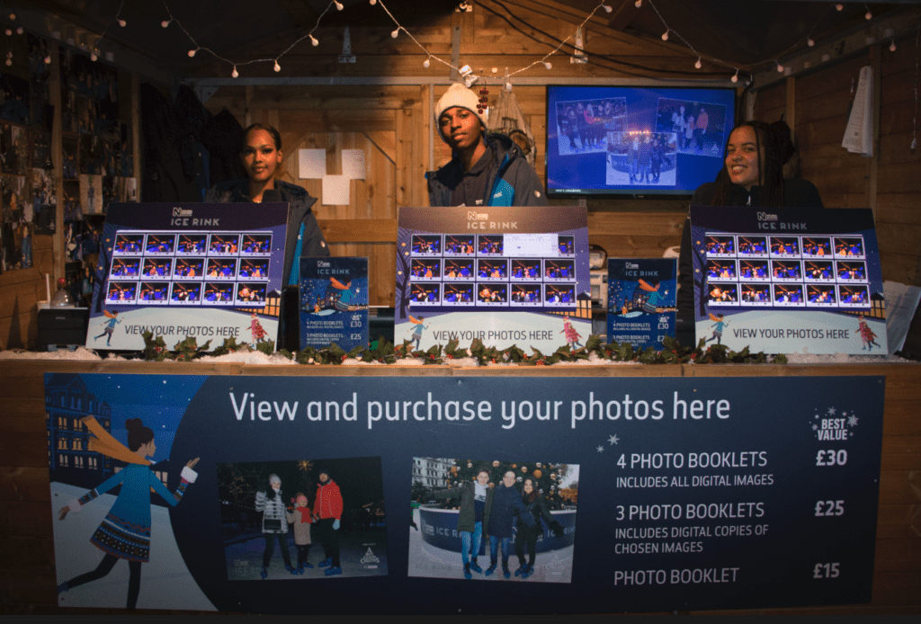 Image of three staff members serving at sales desk offering photo booklets.